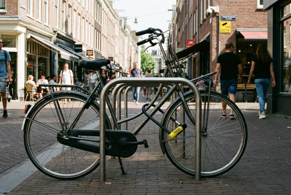 Prawidłowo przypięty rower do stojaka w monitorowanym i ruchliwym miejscu w centrum miasta.